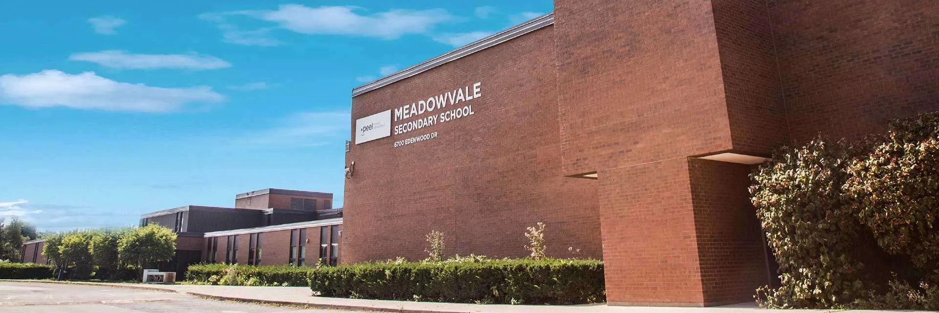 Das große Backsteingebäude der Meadowvale Secondary School ist umgeben von grünen Hecken
