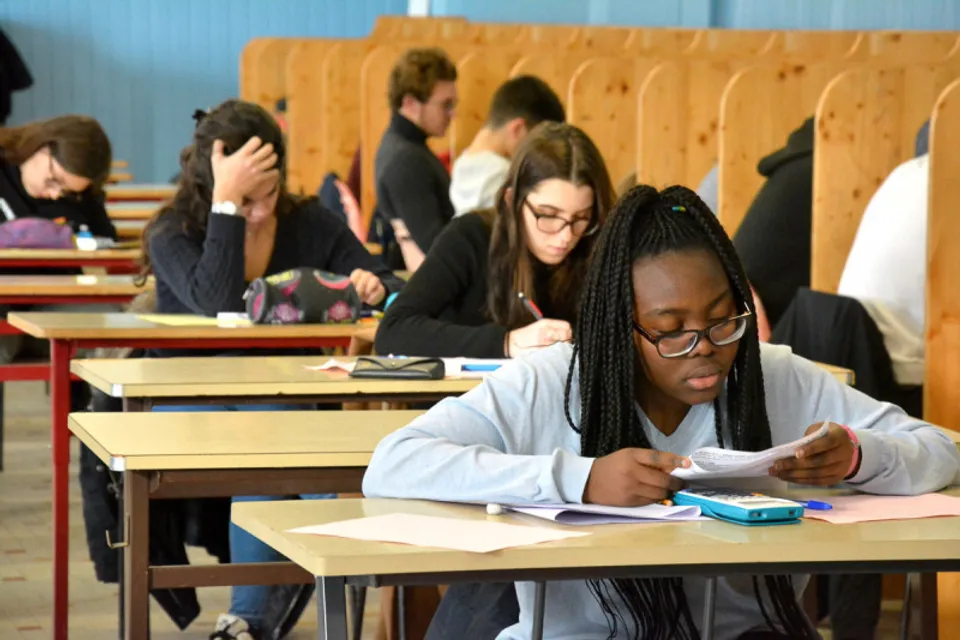Studenti in un'aula del Campus La Salle Saint Christophe scrivono, lavorano con dispositivi elettronici o conversano.