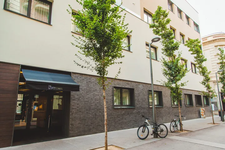 Esterno del campus di Barcellona Centro con facciata bianca e in mattoni e alberi lungo il marciapiede