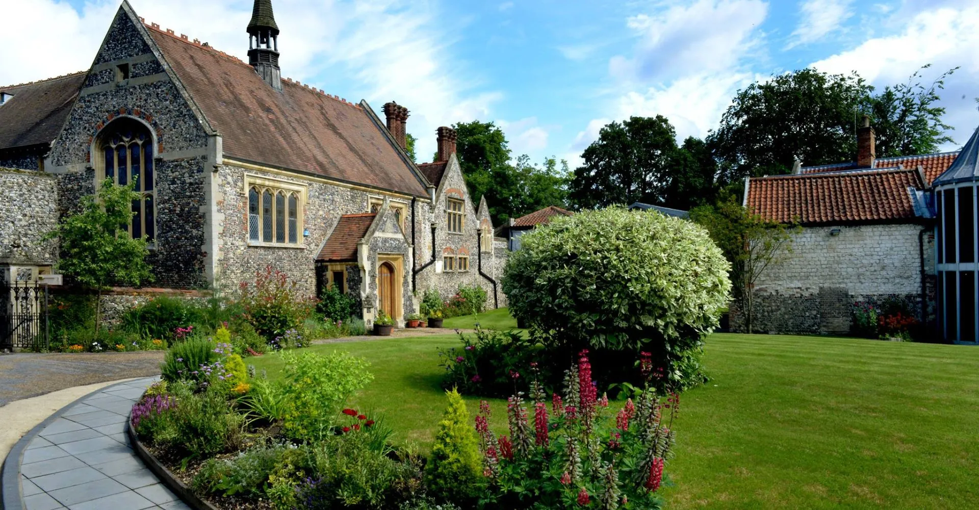La chiesa in pietra con giardino fiorito e prato nel campus della Thetford Grammar School.