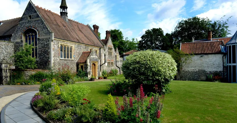 La chiesa in pietra con giardino fiorito e prato nel campus della Thetford Grammar School.