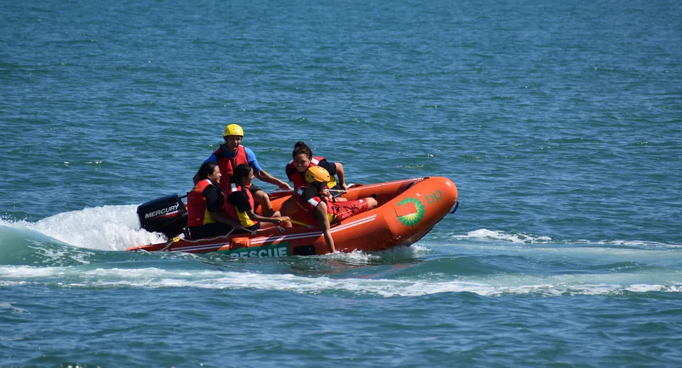 Due studenti del Whanganui City College guidano un gommone arancione sull'oceano agitato.