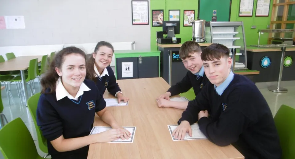 Studenti del Coláiste Mhuire Ballymote in divisa scolastica siedono a un tavolo in classe.