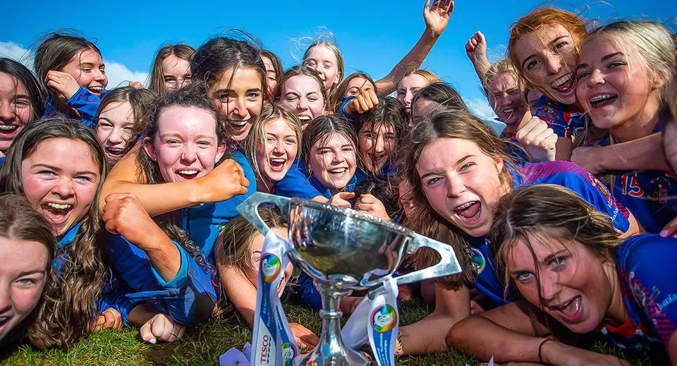 Un gruppo di giovani studentesse della Ursuline Secondary School Thurles posa all'aperto tenendo in mano un trofeo.