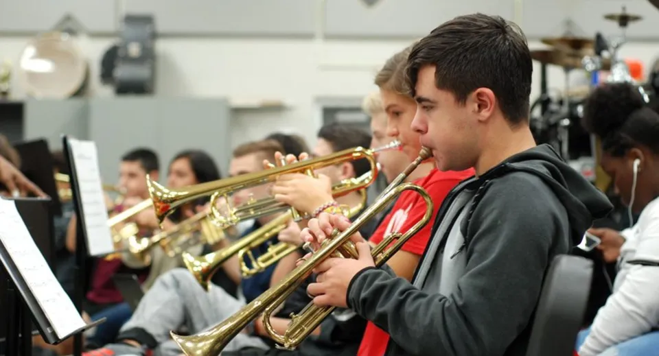 Studenti della The Beekman School suonano strumenti a fiato davanti ad attrezzature musicali.