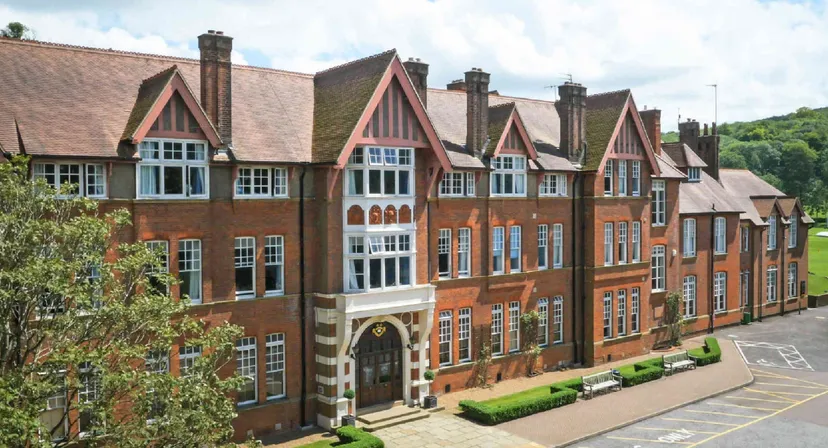 L'edificio in mattoni a più piani della Caterham School in stile Tudor è circondato da un verde rigoglioso.