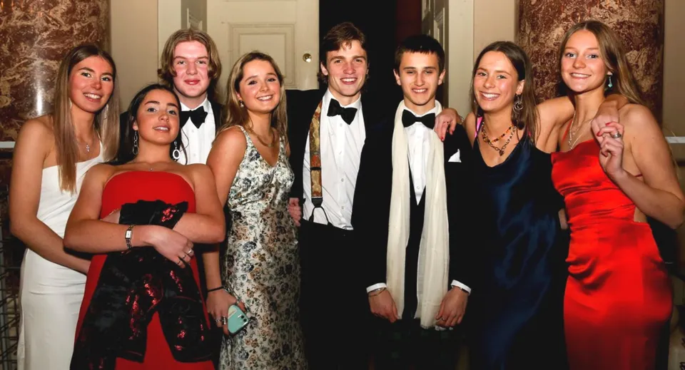 Un gruppo di persone ben vestite a un evento formale nel campus della Stowe School.