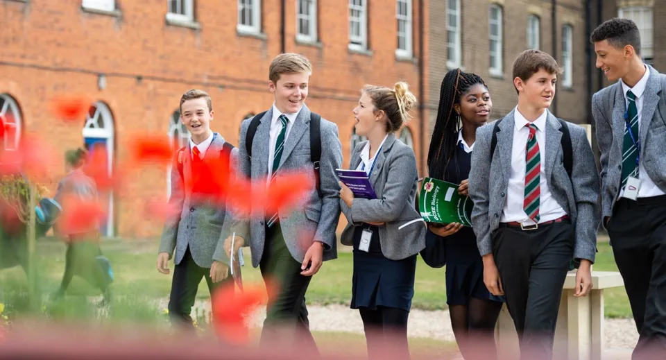 Un gruppo di studenti si trova nel campus del St. Edmund’s College davanti a un edificio in mattoni.