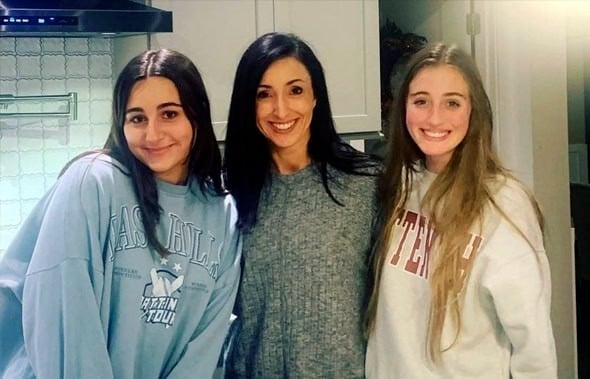 Una mujer y dos jóvenes sonrientes posan juntas en el interior de una cocina