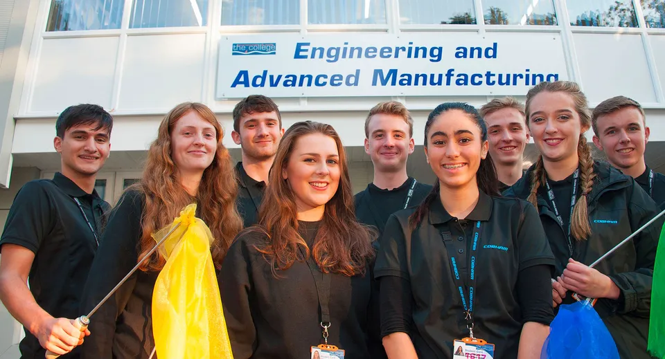 Un gruppo di studenti in toga da diploma si trova davanti all'edificio con il cartello Engineering and Advanced Manufacturing nel campus del Bournemouth & Poole College.