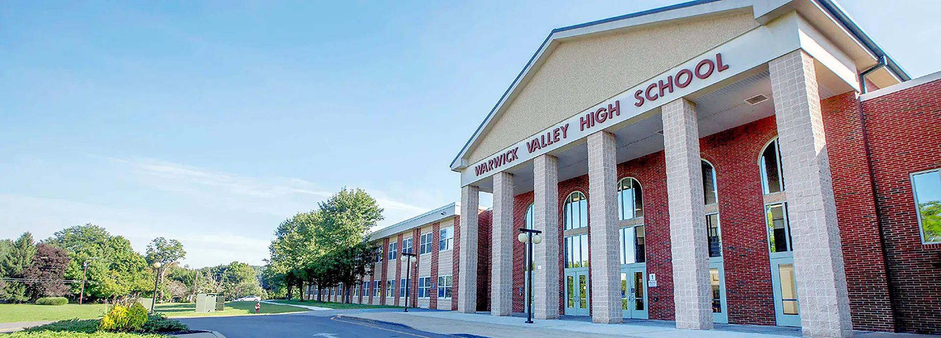L'edificio in mattoni a due piani della Warwick Valley High School è circondato da alberi e da un piazzale pavimentato.