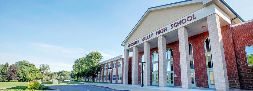L'edificio in mattoni a due piani della Warwick Valley High School è circondato da alberi e da un piazzale pavimentato.