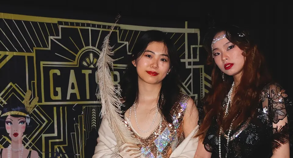 Due studentesse della Malvern St. James Girls' School vestite in stile anni '20 davanti a uno sfondo a tema Gatsby.