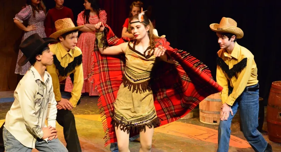 Studenti della Solebury School eseguono una danza culturale tradizionale su un palco con uno sfondo scuro.
