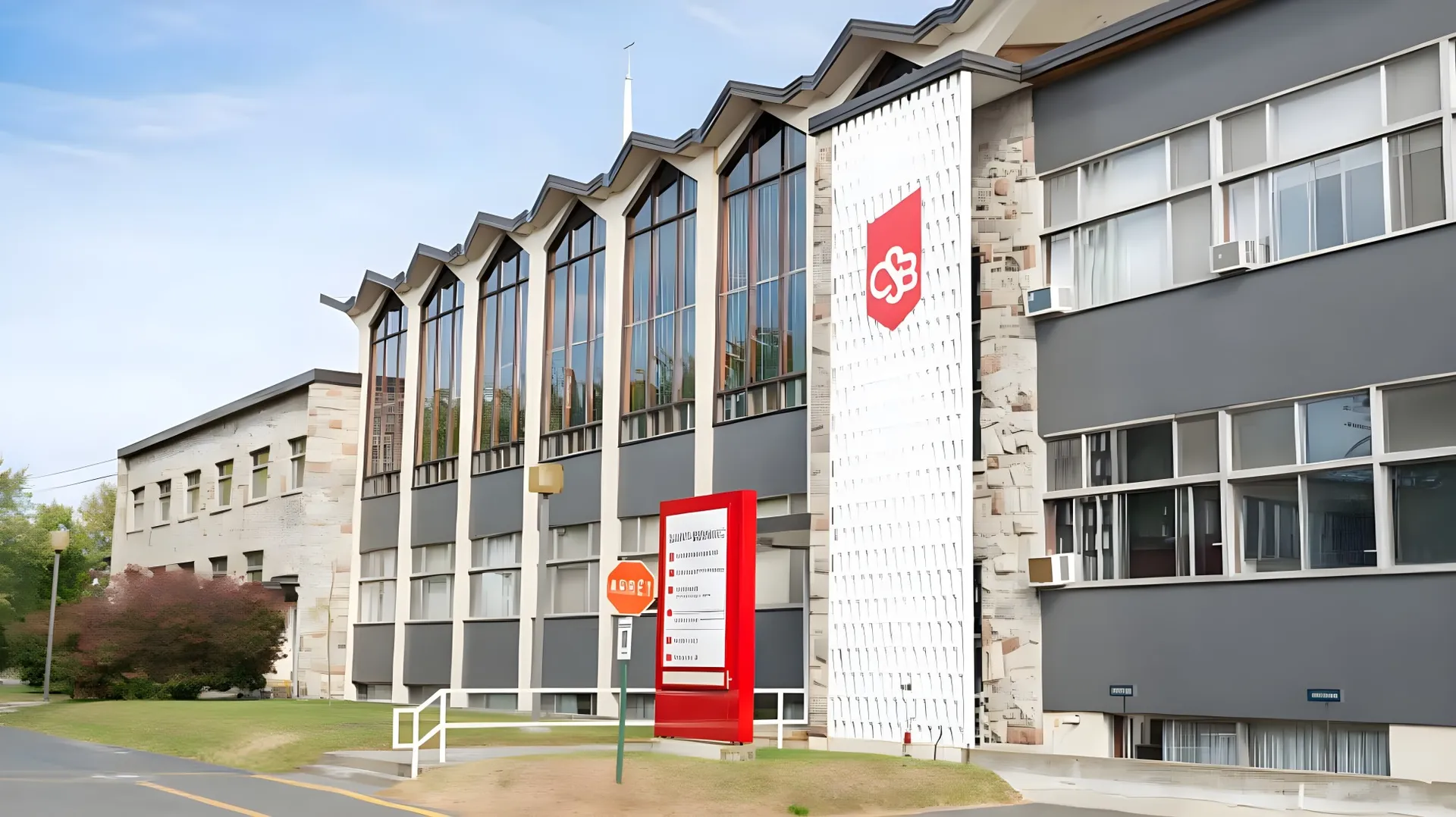 L'edificio a più piani con grandi finestre e logo rosso nel campus del College Saint-Bernard è circondato da un'area verde.