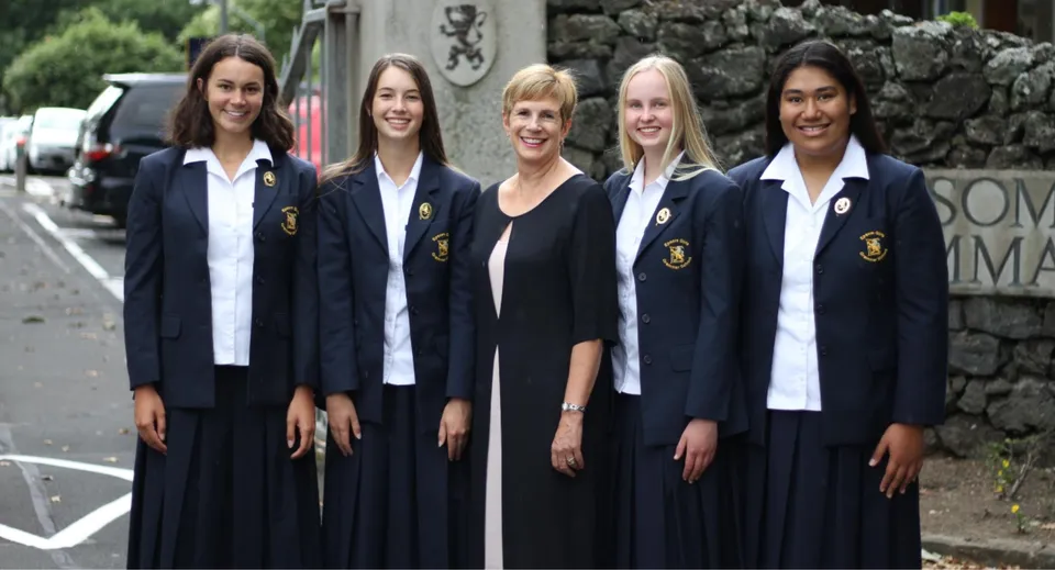 Un gruppo di cinque studentesse della Epsom Girls Grammar School davanti a un muro di pietra.