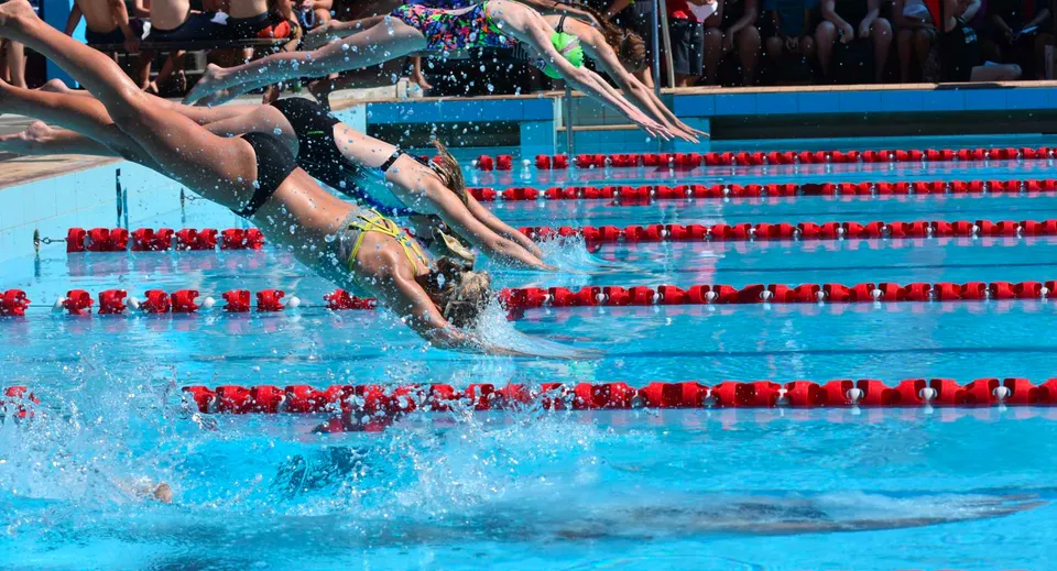 Studenti della Taradale High School si tuffano in piscina con spettatori sullo sfondo.