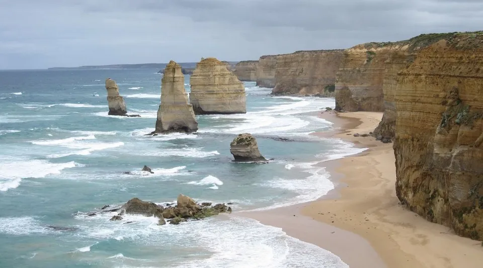L'immagine mostra scogliere rocciose e alte formazioni rocciose su una spiaggia sabbiosa vicino al Manea Senior College.