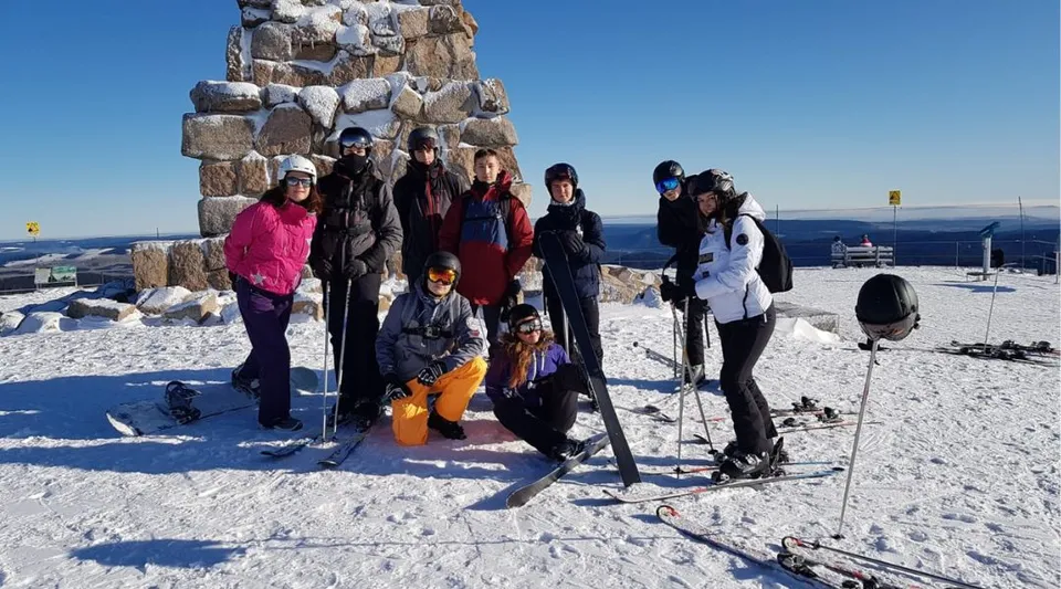 Un gruppo di studenti del Lycée Saint Antoine in abiti invernali si trova davanti a una struttura in pietra su un pendio innevato.
