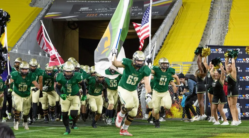 Un gruppo di giocatori di football americano in divisa verde entra in campo nel Chandler Unified School District.