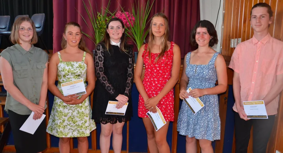 Un gruppo di giovani donne della Motueka High School è insieme sul palco e tiene in mano dei certificati.