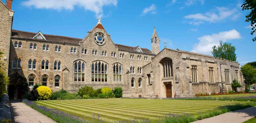 L'edificio principale storico della Stamford Endowed Schools con una torre dell'orologio e un giardino ben curato in primo piano.