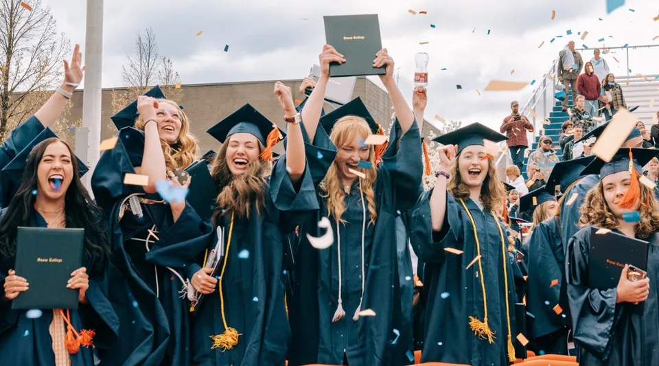 Un gruppo di diplomati in toga nera festeggia la propria cerimonia nel campus del Snow College.