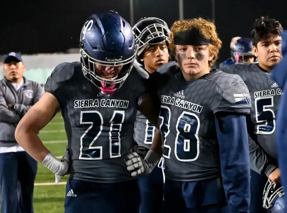 Giocatori di football americano della Sierra Canyon School con maglie scure sul campo da gioco.