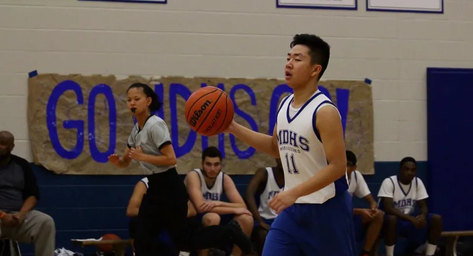 Due giocatori di basket della Markham District High School lottano per la palla sul campo durante una partita.