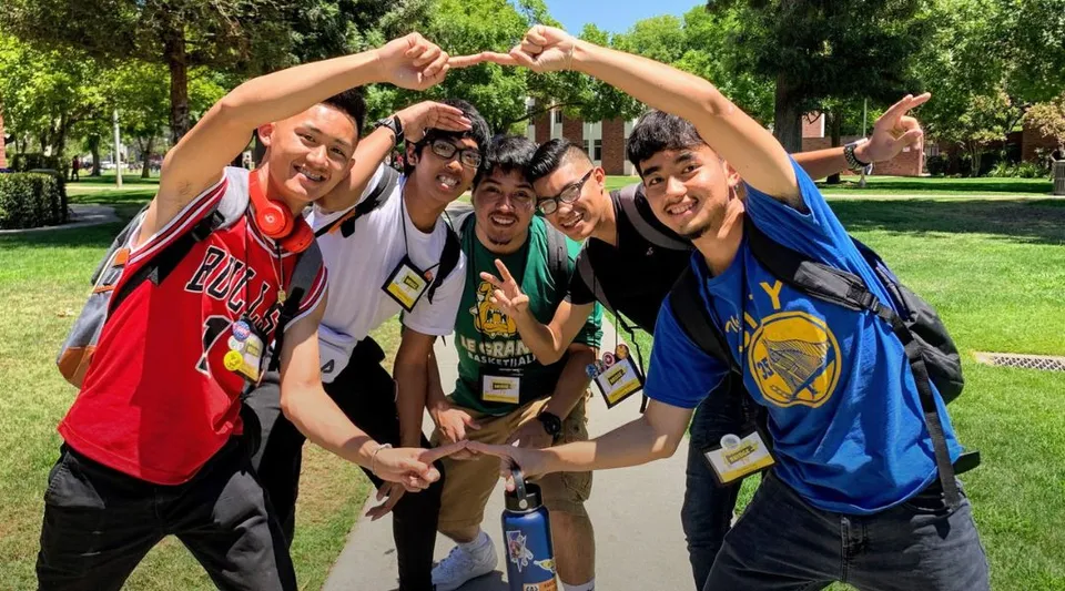 Un gruppo di studenti in posa nel parco davanti agli alberi nel campus della California State University Long Beach.