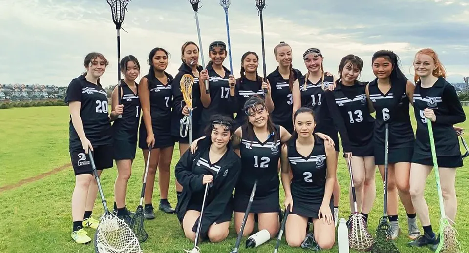 Un gruppo di studentesse in divisa scolastica nera posa su un campo da gioco nel campus del Selwyn College.