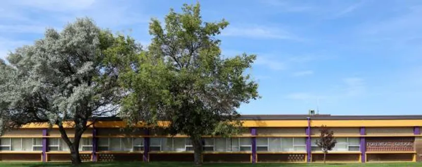 L'edificio scolastico moderno della Foremost School è incorniciato da una chioma verde ed è visibile contro un cielo blu.