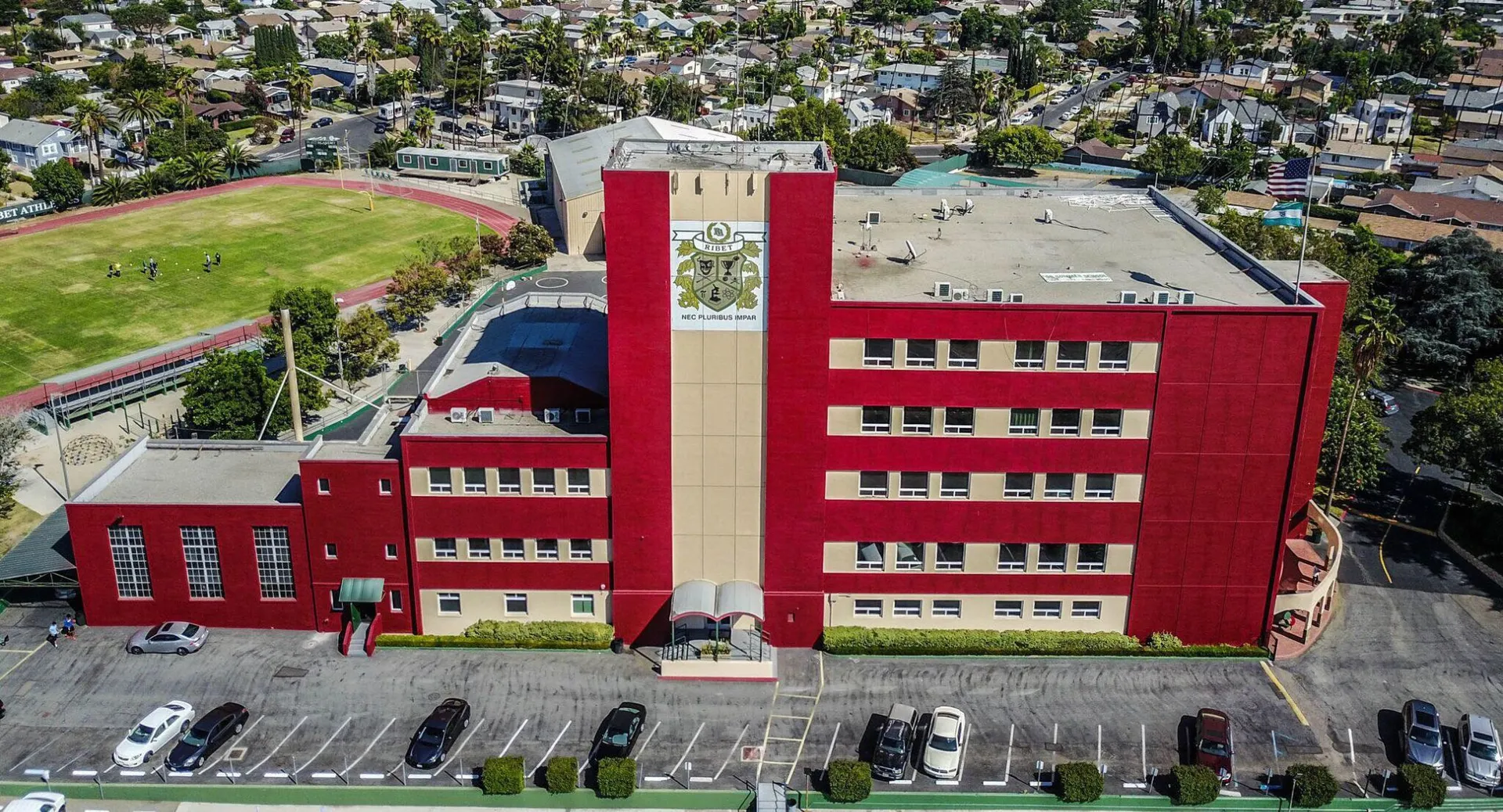 Un grande edificio rosso della Ribet Academy si erge davanti a un vasto paesaggio urbano.