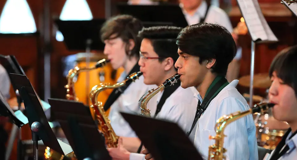 Un gruppo di studenti del Botany Downs Secondary College suona diversi strumenti a fiato su un palco.