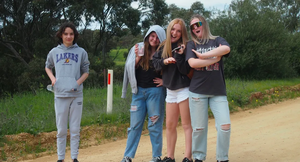 Quattro studentesse insieme in un ambiente naturale con alberi nel terreno della Kapunda High School.