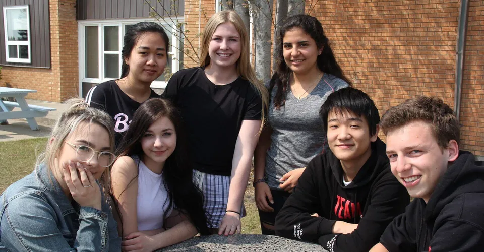 Un gruppo di studenti e studentesse si trova davanti a un edificio in mattoni nel campus del Waterloo Region District School Board.
