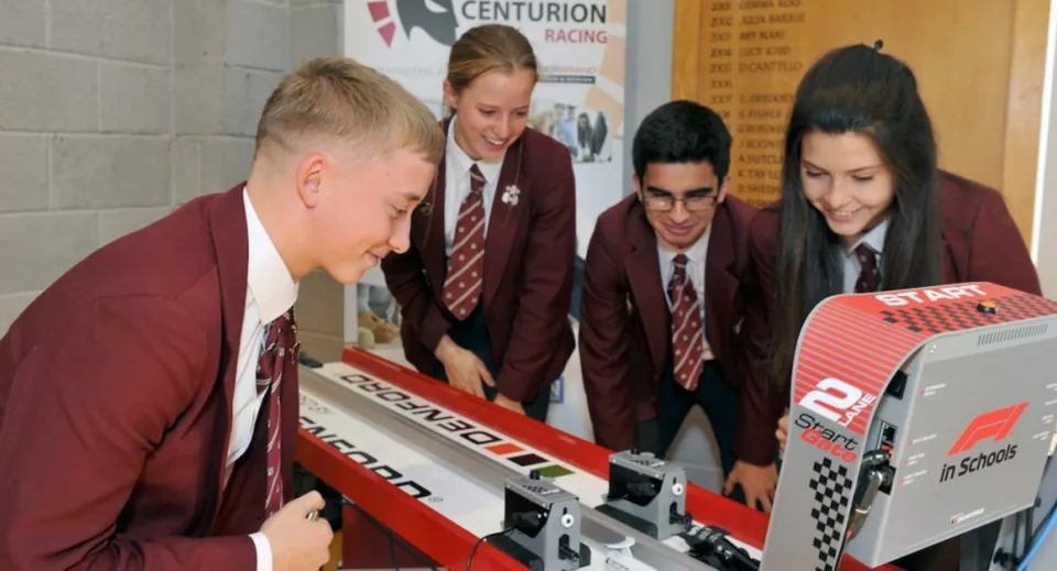 Studenti della Rishworth School in uniforme scolastica si radunano attorno a un simulatore di guida e partecipano a un'attività.