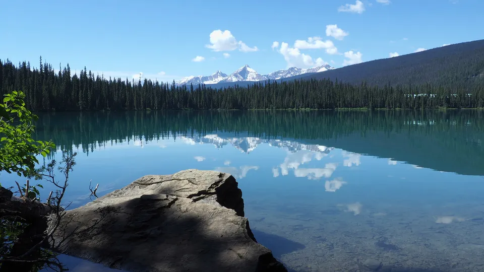 Un limpido lago di montagna con il riflesso delle cime innevate sullo sfondo della Langley Secondary School.