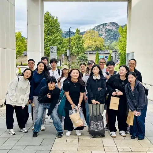 Eine Gruppe junger Menschen steht vor einem Gebäude auf dem Campus der Taejon Christian International School.