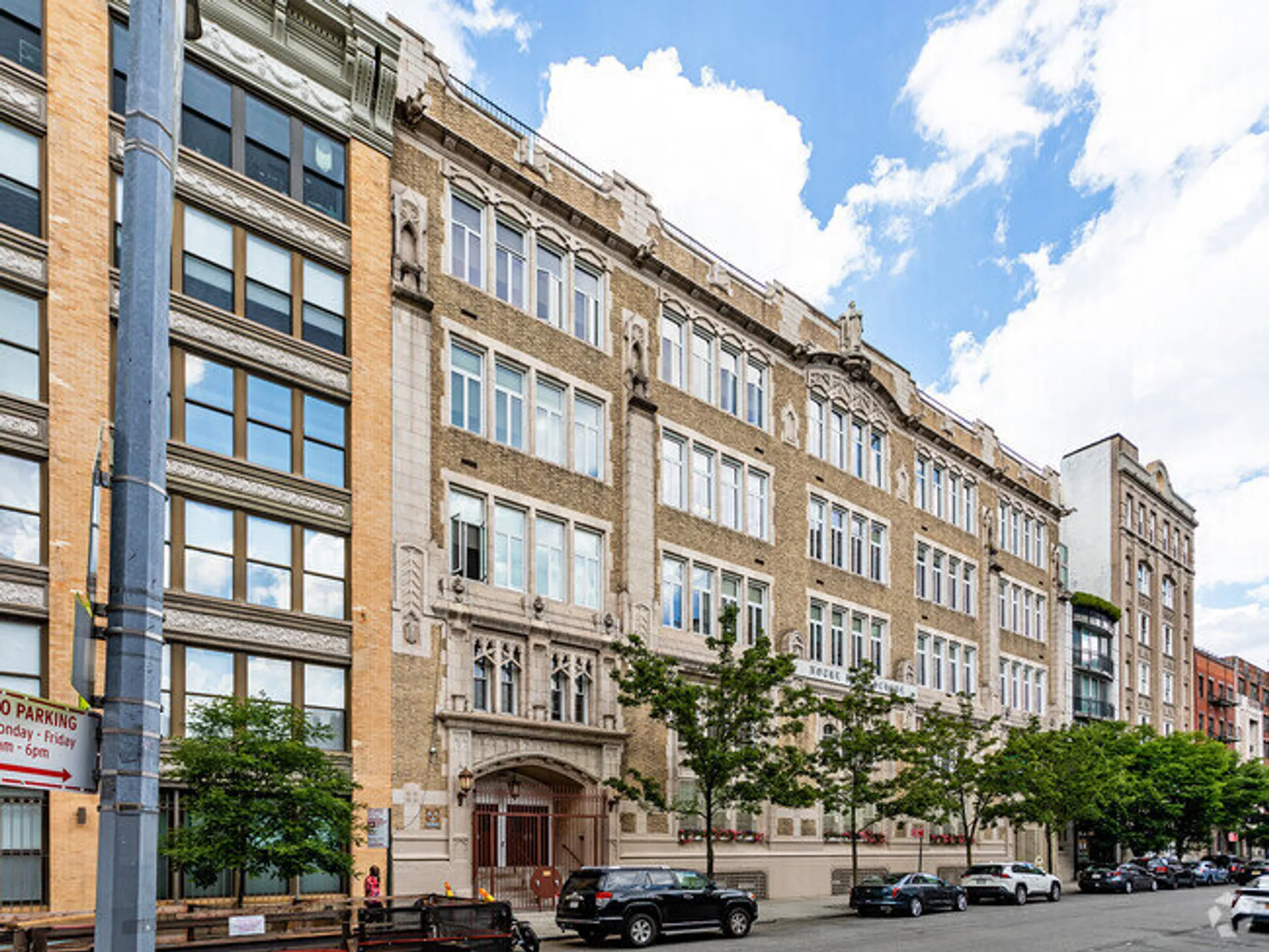 L'edificio in mattoni della Notre Dame High School mostra un'architettura a più piani con molte finestre e decorazioni sotto un cielo blu.