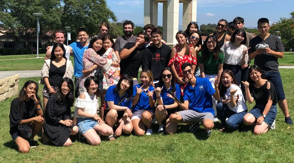 Un grande gruppo di giovani si raduna su un prato nel campus della The Academy MiraCosta.