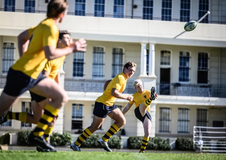 Studenti di The Scots College giocano a rugby sul campo sportivo davanti all'edificio scolastico.