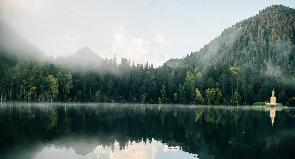 Un lago tranquillo con un bosco verde e montagne che si specchiano nell'acqua, vicino alla St. John’s-Kilmarnock School.
