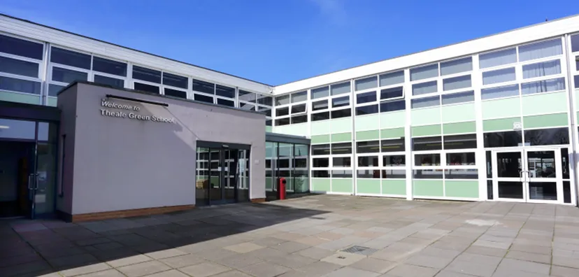 L'edificio scolastico moderno a più piani della Theale Green School con ampie finestre sotto un cielo limpido.