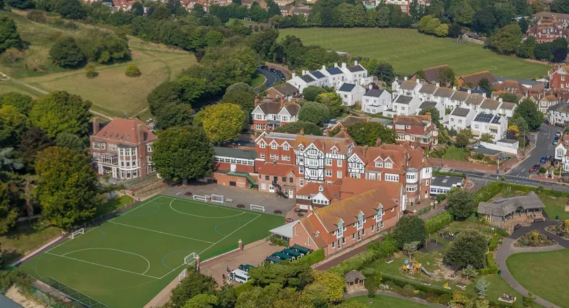 Foto aerea del villaggio con edifici tradizionali in stile Tudor e campo da calcio vicino alla Bede's Senior School.