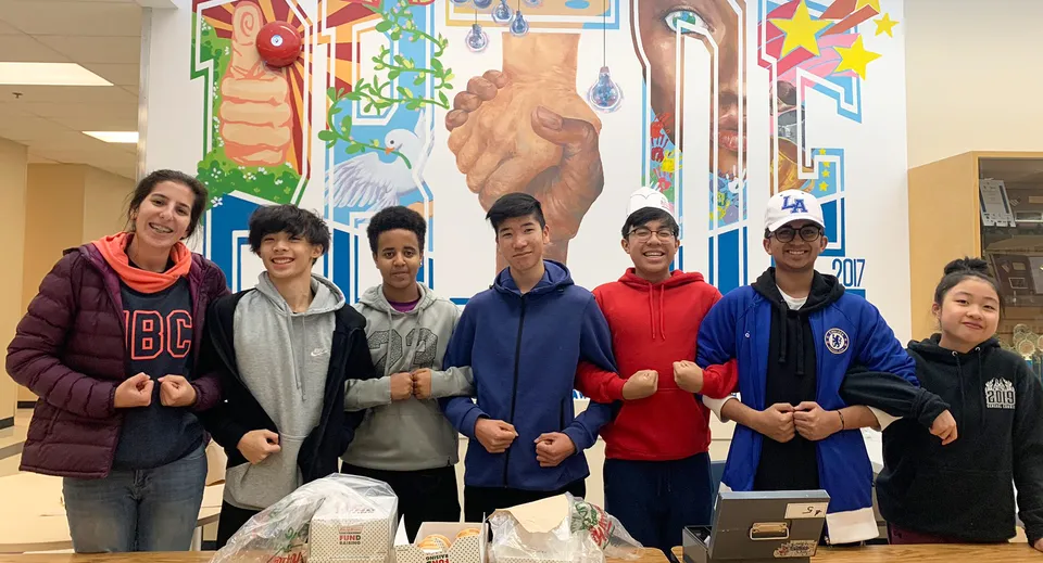 Un gruppo di studenti si trova davanti a un murale colorato nel campus della R.C. Palmer Secondary School.