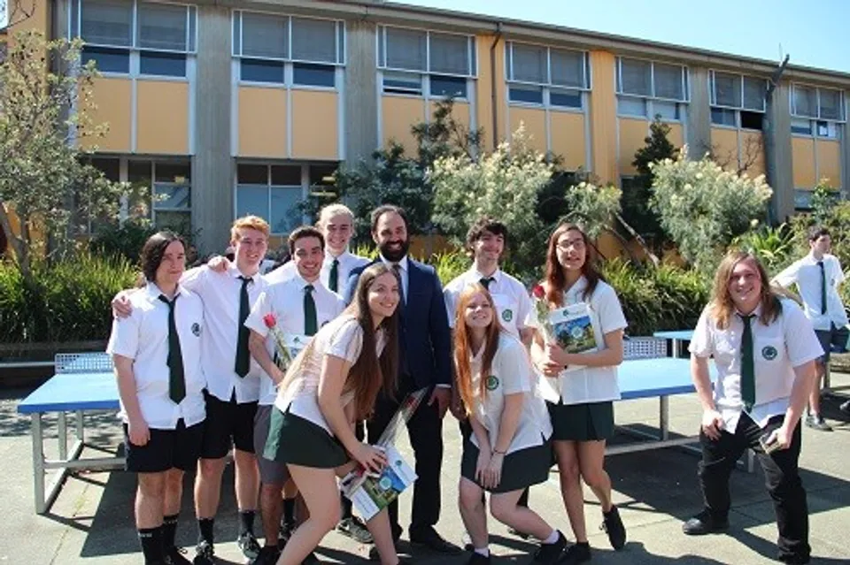 Un gruppo di studenti è in piedi davanti a un edificio con grandi finestre nel campus della The Forest High School.