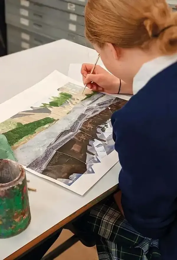 Studentessa in divisa dipinge un acquerello durante una lezione d'arte a scuola