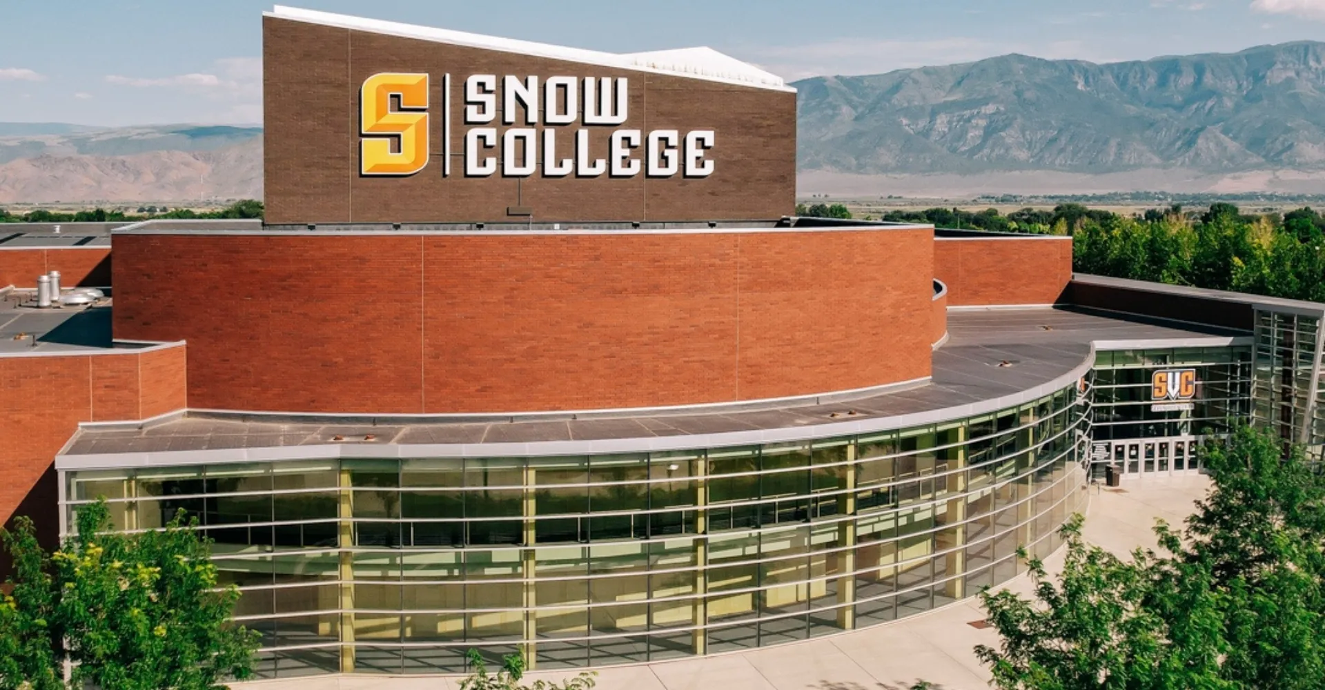 L'edificio moderno del Snow College si trova davanti a uno sfondo montuoso sotto un cielo azzurro e limpido.