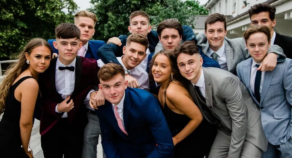 Un gruppo di studenti della Abbotsholme School posa all'aperto davanti ad alberi ed edifici per una foto di gruppo.